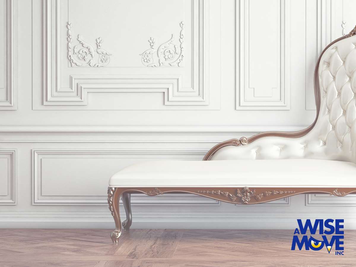 A sophisticated chaise lounge with baroque styling represents moving antique furniture, poised in an elegant room with decorative wall paneling.